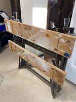 Side view of the workbench showing the wooden vice jaws with holes, paint splatters and heavily used condition.