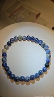 Photo of a single stretchy bracelet made of round sodalite beads arranged in a circle on a white background under light.