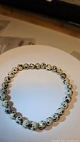 Close-up image of a natural Dalmatian Jasper beaded stretchy bracelet showcasing round spots on the beads, strung on an elastic band.