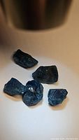 Five natural blue apatite rough crystals of varying shapes and sizes on a white background.