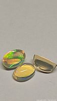 Three natural untreated Ethiopian opal cabochon gemstones with multicolored flashes.