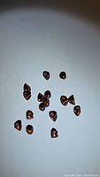 Multiple small fancy bullet cut natural almandine garnet gemstones arranged on a flat surface.