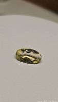 Photo showing the natural oval cut lemon citrine gemstone with light yellow color and faceted surface.