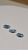 Three marquise cut sky blue topaz gemstones displayed on a white background, showing their cut, clarity, and light reflection.