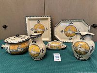 Six hand-painted pieces arranged on green cloth against wood backdrop showing full lot design