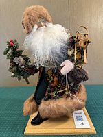 Full view of Lynn Haney collectible Santa figurine displaying animal patterned coat and winter accessories including a sled and pine cones.