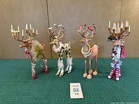Group shot of four reindeer figurines on green surface.