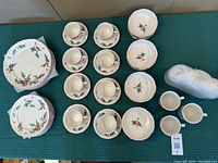 Top-down view of complete set: 2 dinner plates, 2 salad plates, 2 bowls, 2 cups with saucers and 4 mugs arranged on green surface.