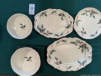 Overhead view of all five pieces (two bowls, two oval platters, one round platter) on green background