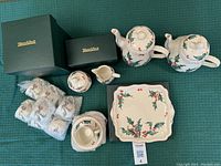 Overall view of all pieces, including boxed items, bubble-wrapped cups and saucers, teapot, coffee pot, sugar bowl, creamer, and cake plate.