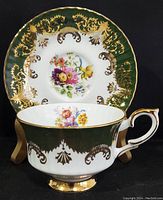 Front angle view of teacup in front of saucer showing the floral design and gold detailing on both items