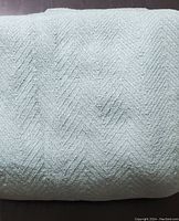 Full view of folded pale green cotton blanket showing texture and color.