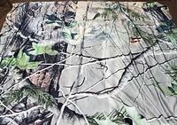 Duvet cover and pillowcase spread out flat showing detailed nature print including tree branches, bark, and green leaves on a light background.