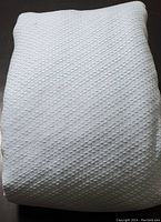 Folded bedspread showing textured diagonal basketweave pattern and overall color.