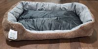 Rectangular dog bed with raised brown shaggy edges and gray inner sleeping area