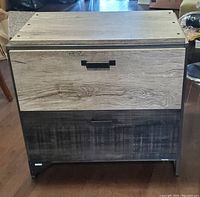 Front view of the lateral file cabinet with two drawer fronts showing rustic gray wood grain and black metal handles.