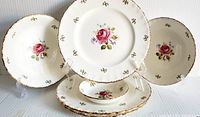 Set of six Grindley dishes with floral rose design and scalloped edges edged in gold, displayed upright and stacked