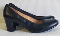 Side profile view showing the shape, heel height and overall style of the black pumps.