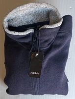 Folded navy blue men's sweater with zipper and gray inner collar, tag attached showing Livergy brand.