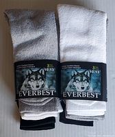 Two separate photos showing six pairs of EVEREST men's sports socks in original packaging, three pairs per pack, in grey, white, and black.