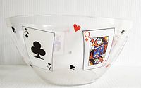 Side view of a clear glass bowl decorated with playing card images including an Ace of Clubs and Queen of Diamonds