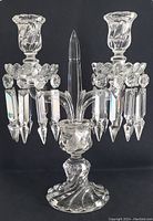 Full front view of crystal two-light candelabra showing swirl base, central finial, candle cups, bobeche and prisms.