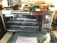 Photo of Breville Mini Smart Oven showing front with metal handle, glass door, control knobs and buttons.