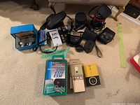 Top view of the camera, lenses, film rolls, and accessories arranged on carpet.