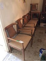 Four wooden dining chairs with curved top rails and upholstered tan seats arranged in a row.
