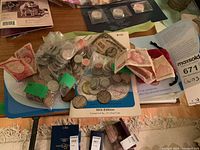 Top view of a table with loose coins in bags, rolled coins in paper tubes, foreign banknotes, and coin booklets.