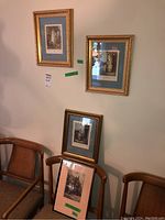 Four framed artworks: Two engravings and two etchings, showing detail on wall and chairs below, all framed in gold frames with blue matting.
