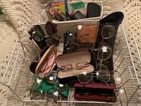 White fabric bin containing eyeglass frames, sunglasses and cases on knit blanket