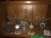 Lot of Imperial Glass Cornflower pattern items with salt and pepper shakers, covered dishes, plates, and glasses arranged on wooden shelf.
