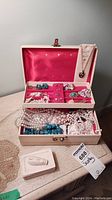 Full view of jewellery box open showing beaded necklaces, earrings, brooches, and pendant necklace.