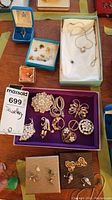 Overall lot on tabletop showing boxes of earrings, rings, necklaces and tray of brooches