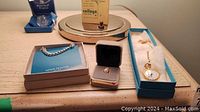 Full lot arrangement on table showing bracelet, tie tack, pearl ring, and Birks watch pendant necklace in box
