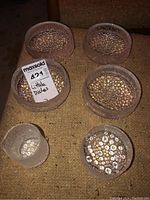 Six Iittala glass dishes shown from above on a brown surface: five bowls and one pitcher with bubble interior design.