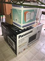 Panasonic NN-SD664W microwave in white box with personal cooler box stacked on top.