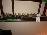 Wade Whimsies figurines displayed on shelves, a mix of animals and human figures with the label 'Red Rose Figures'