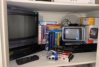Shelf overview showing Sony CRT TV, Panasonic portable TV, VHS players and movie collection
