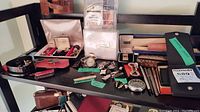 Overview of shelf top showing watch, cufflinks, badges, knives, pens, money clip, handkerchiefs, wallet