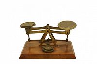 Brass twin-pan balance scale on wood base with removable weight on platform