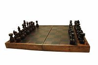 Wooden chess set with dark and light classic chess pieces arranged on an open folding wooden chess board, wood grain finish visible.