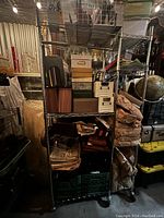 Full view of a metal wire rolling shelf filled with boxes and miscellaneous stored items, shelf dimensions 178"H x 48"W x 14"D.