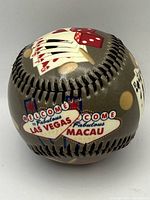 Decorative baseball showing casino themed artwork with cards, dice, and Las Vegas and Macau signs