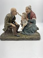 Full view of the grandparents figurine with child, showing all three figures seated and interacting on a base.