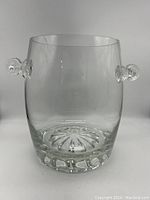 Front angled view of the clear crystal champagne bucket showing one handle and starburst base inside.