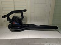 Side profile of the black Toro Super Blower Vac electric leaf blower and vacuum showing handle and long nozzle