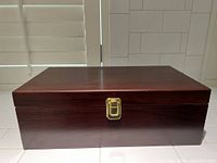 Closed wooden box with brass latch, polished dark wood finish.
