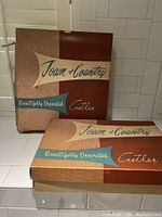 Two Town & Country Cutler original boxes on a white tiled surface.